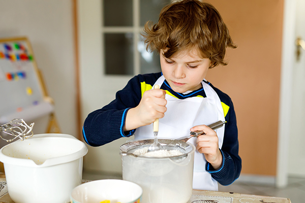 Pictured is a boy cooking in his home. Pictures is a boy cooking in his home.