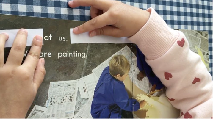 A St Gertrudes Catholic Primary School Smithfield kindy student uses two strips of paper to isolate two words within a full sentence