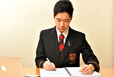 Damon Lam, writing in a workbook.