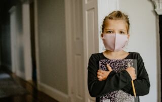 A girl wearing a COVID mask holding a book