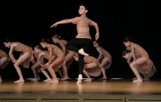 A group of primary school students dance on stage at a Sydney Catholic Schools Eisteddfod event.
