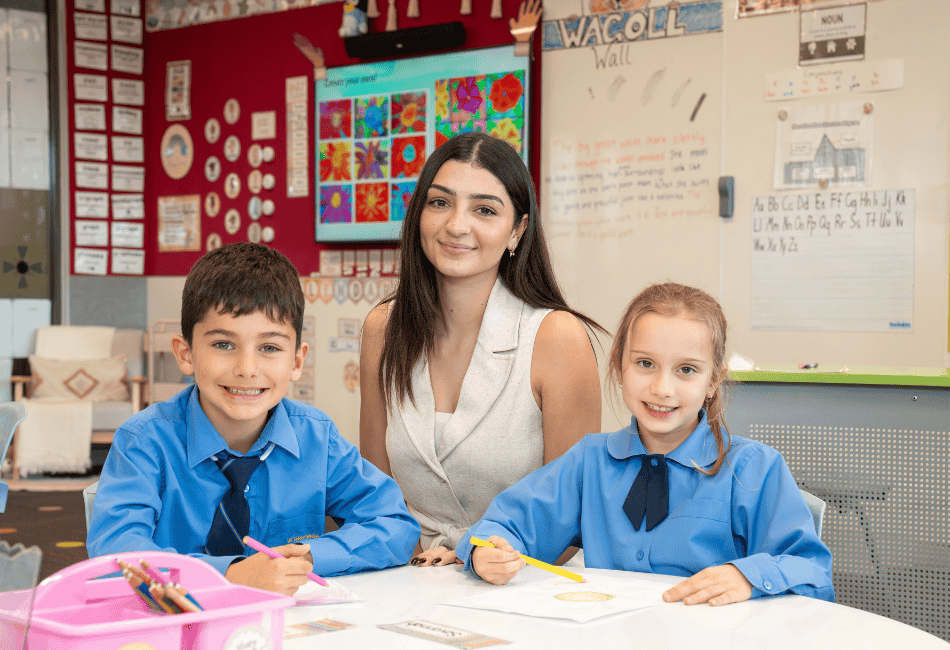 A photo of a teacher smiling at the camera with two happy students