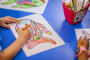 A small child works on a fish drawing
