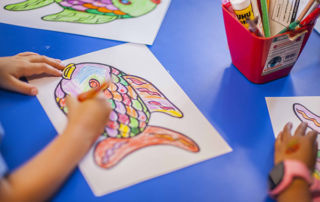 A small child works on a fish drawing