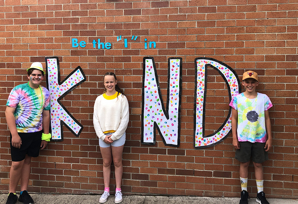 St John Bosco Catholic Primary School Engadine students standing in front of a 'Be the I in Kind' mural