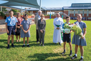 Holy Spirit Carnes Hill school captains, Mia Yenco and Matthew Sanasi, present the governor of NSW with flowers and a gift