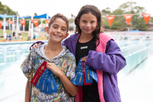 Sibling swimmers with ribbons from the swimming carnival