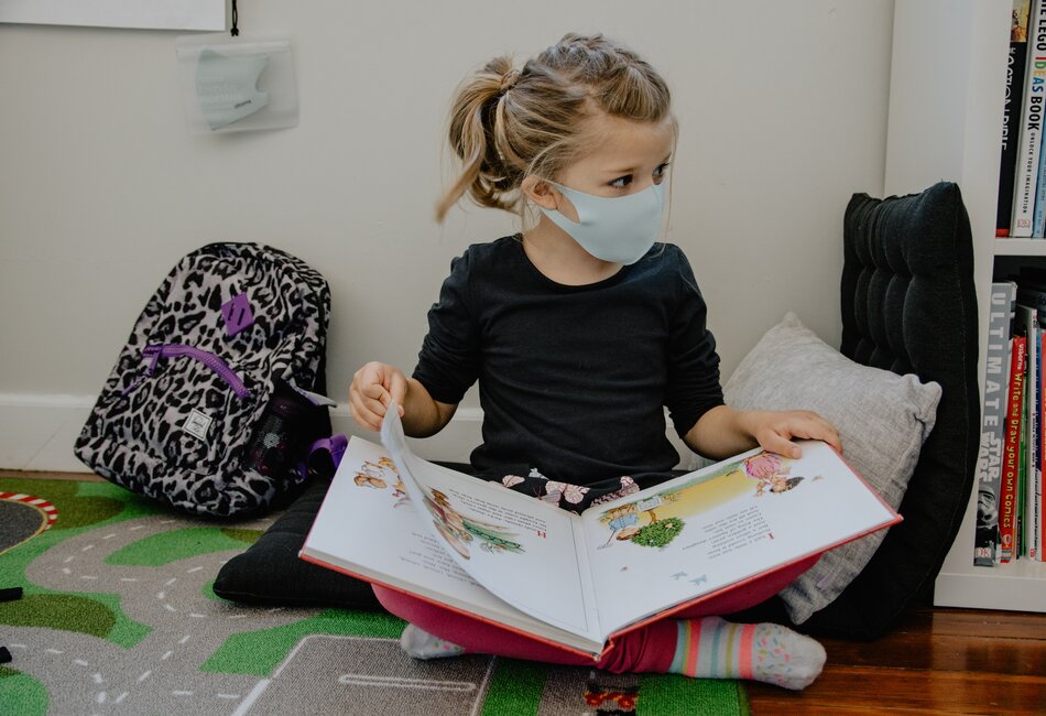 Student reading a book wearing a COVID-19 mask
