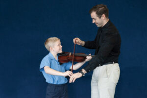 Sydney Catholic Schools' Amadeus Music Education Program student being taught how to play a violin by his music teacher
