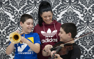 Twins Samuel (trumpet) and Joseph abou Arrage (viola), pictured with mum Nidal, receive music tuition through Sydney Catholic Schools' Amadeus Music Education Program.