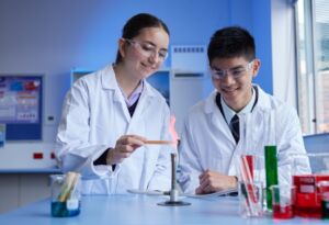 Students complete a chemistry experiment with bunsen burner in a high school science lab.