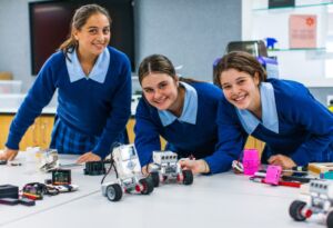 Female students build robotic devices as part of their STEM learning.