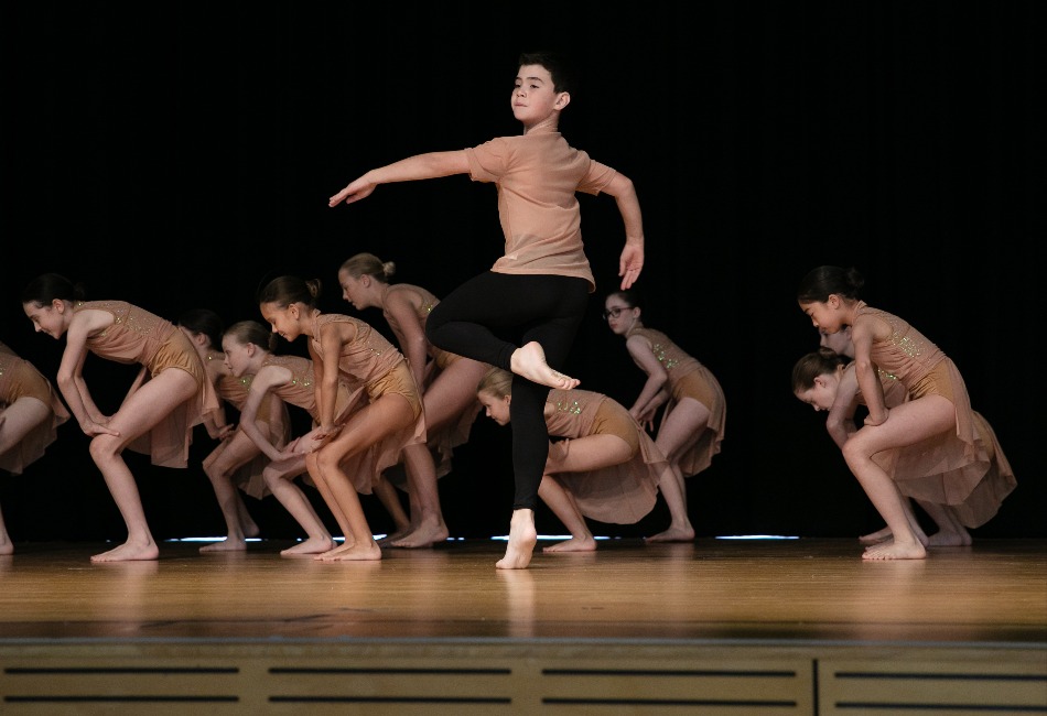 A group of primary school students dance on stage at a Sydney Catholic Schools Eisteddfod event.