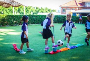 Kindergarten students play sport outdoors at school.