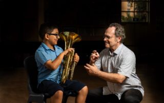 A student learns a brass instrument with an Amadeus Music Education Program tutor.