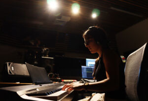 Student behind a sound mixing board at a performance event.