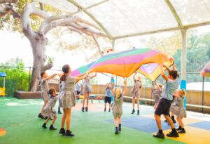 Primary school children gather around a parachute for play.