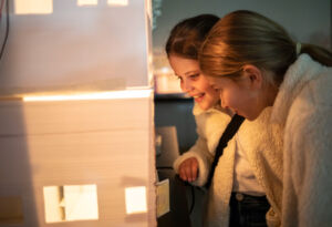 Students admire a model house and its lighting.