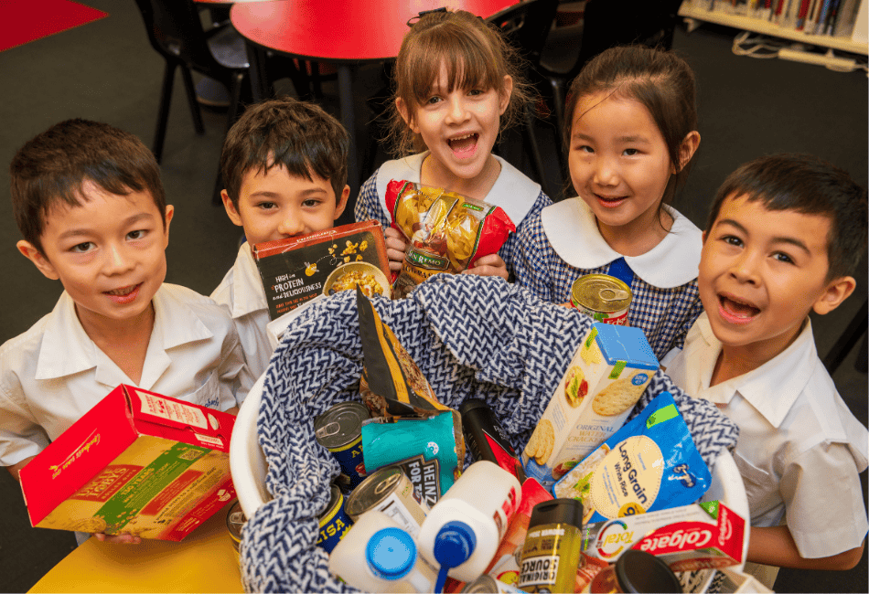 Five students surround a Christmas hamper with groceries and essentials