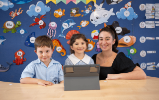 Photo of two students with a teacher in a classroom