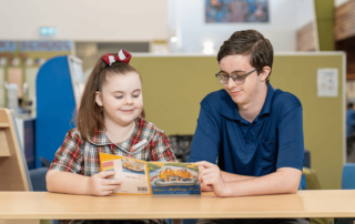A photo of a School-Based Education Support (SBES) Trainee working with a happy student