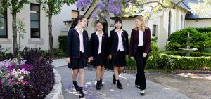 Three students walking through a garden with a Principal